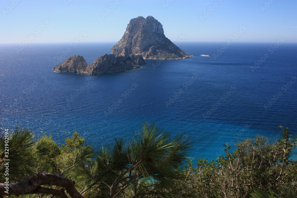 The magical island of Es Vedra with the small islet of Es Vedranell next to it in front of the coast of Cala d'Hort in the tourist island of Ibiza in the midst of nature between cliffs,