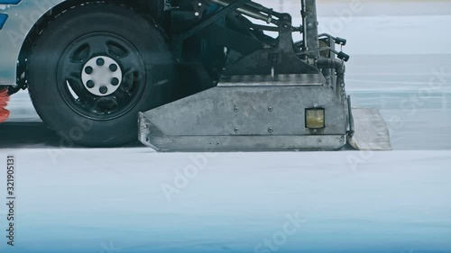 Zamboni resurfacing an indoor skating rink. Slow Motion. Ice resurfacer cleaning ice, machine cleaning and polishing smooth icerink. Ice harvester or restores ice. photo
