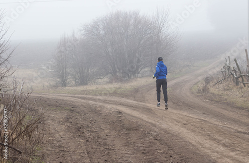 Young sporty girl goes running in the nature Beautiful foggy morning Moody atmosphere