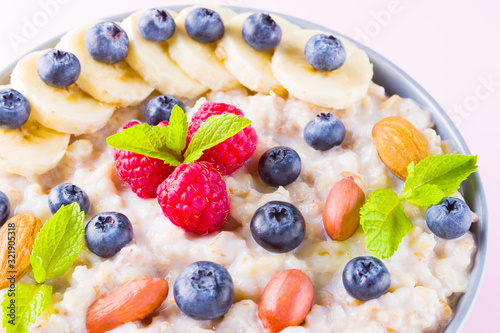 Healthy breakfast. Bowl of oatmeal porridge with fresh blueberries, raspberries, almonds and banana. Clean eating, dieting, detox, vegetarian food concept. Healthy lifestyle concept