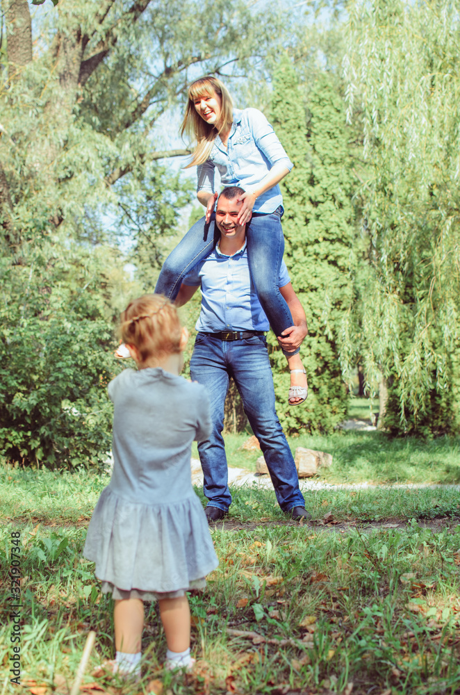 family shot in the park, summer day.  .a guy with a girl dressed in a denim suit. very happy, cheerful and in love