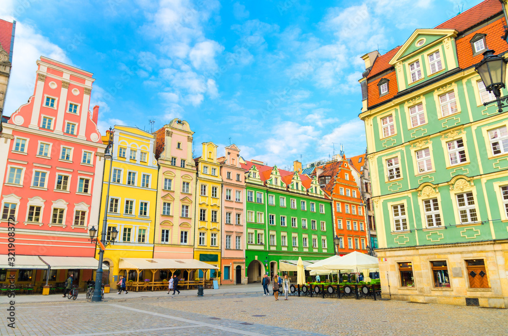 Row of colorful traditional buildings with multicolored facades and street lamp on cobblestone Rynek Market Square in old town historical city centre of Wroclaw, blue sky background, Poland