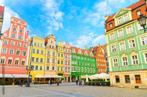 Row of colorful traditional buildings with multicolored facades and street lamp on cobblestone Rynek Market Square in old town historical city centre of Wroclaw, blue sky background, Poland