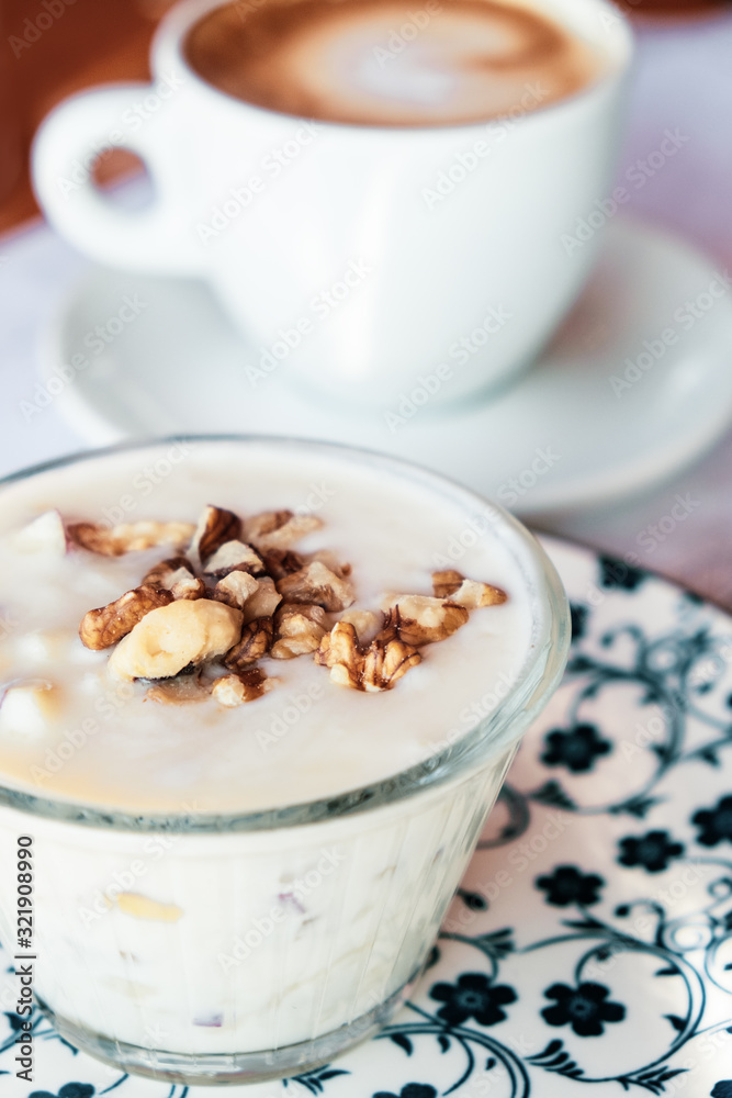 Albanian yogurt dessert with honey and walnuts nuts over white plate Albanian yogurt dessert with honey and walnuts nuts over white plate