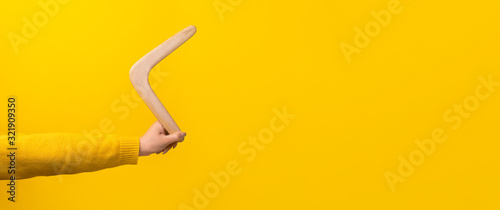 boomerang in female hand over yellow background, panoramic mock-up