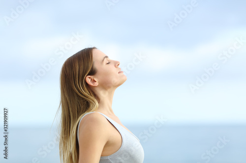 Profile of relaxed girl breathing fresh air on the beach photo