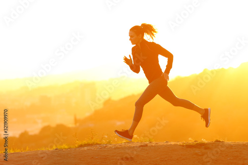 Silhouette of runner woman running at sunset