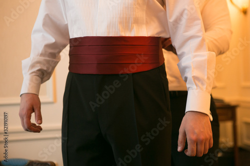 The Elegant man dresses red cummerbund in his wedding day photo