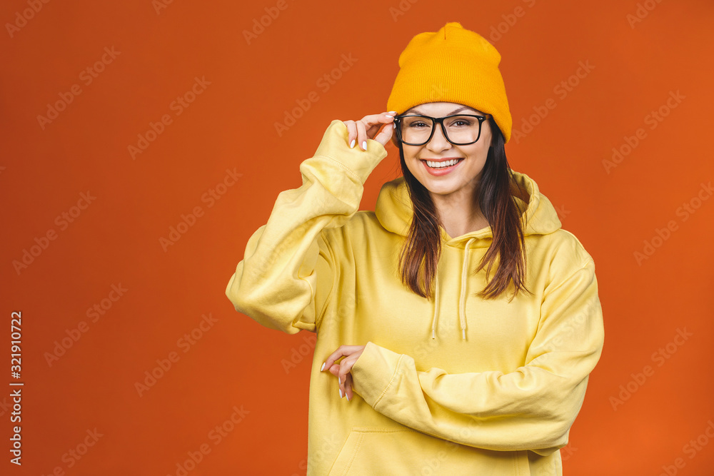 People, youth, leisure and lifestyle concept. Fashionable beautiful young Caucasian young female student wearing stylish clothing laughing, pointing finger. Isolated over orange. 
