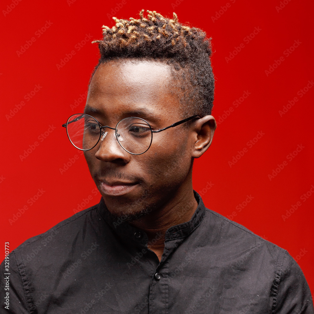 Fototapeta premium Portrait of an African man on a red background. Studio shooting