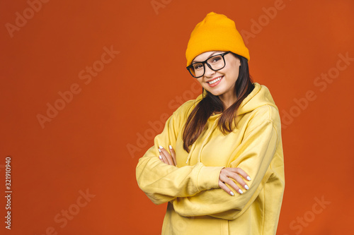 People, youth, leisure and lifestyle concept. Fashionable beautiful young Caucasian young female student wearing stylish clothing laughing, pointing finger. Isolated over orange.  © denis_vermenko