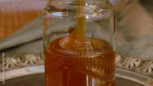 Close up shot of a jar being filled with honey after the honey extraction process photo