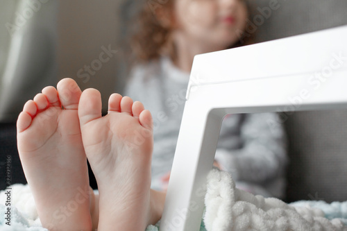 Close-up of the kids foot sit on the bedroom. The skin of barefoot is photo