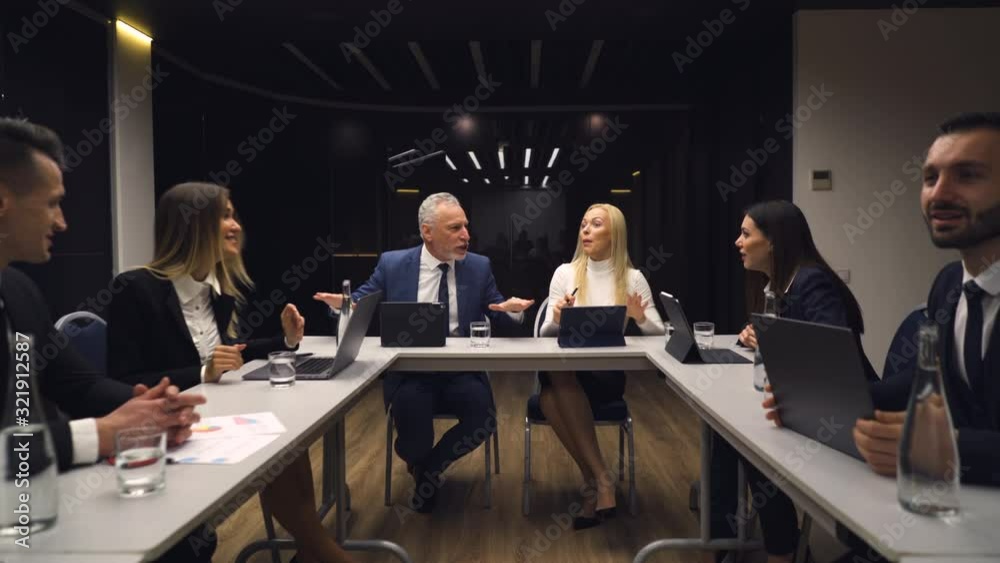 The business people sitting at the table and discuss emotionally