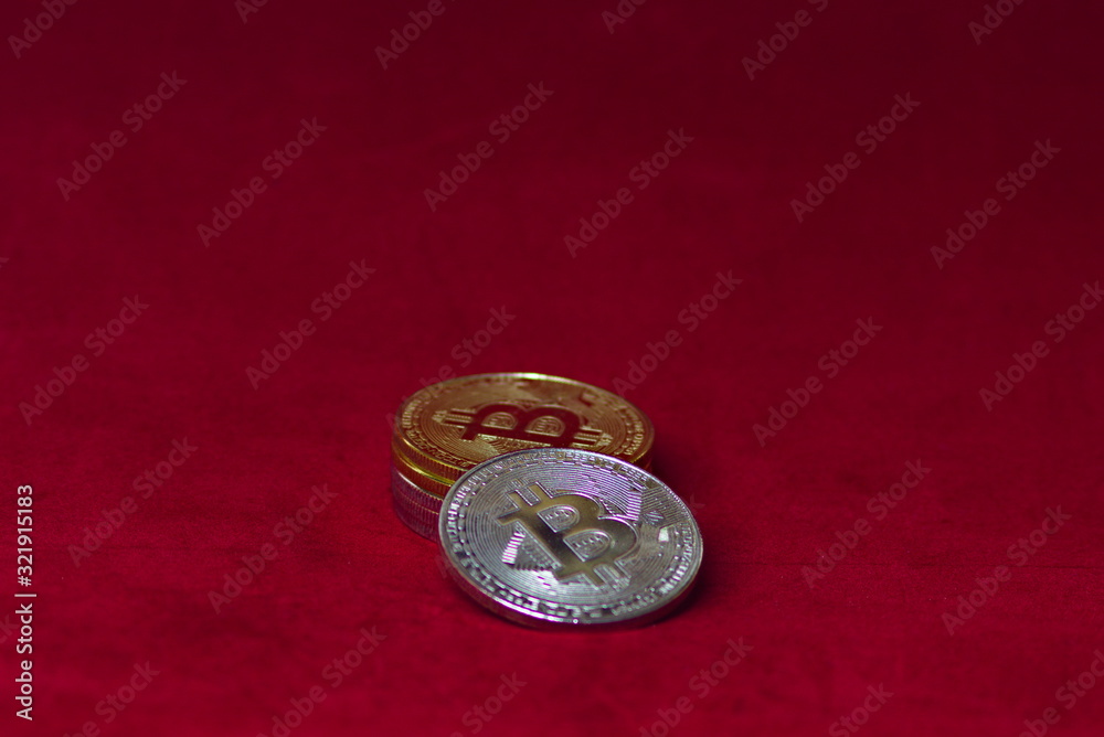 a stack of silver and gold bitcoin cryptocurrency coins on a red velvet background