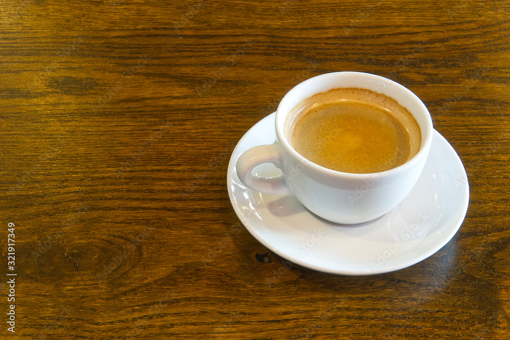 Cup of coffee on wooden table in restoran or coffee house. White ceramic cup view above with copy space Cup of coffee on wooden table in restoran or coffee house. White ceramic cup view above with copy space