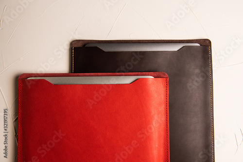 red and brown laptop case on a white concrete background made of genuine leather