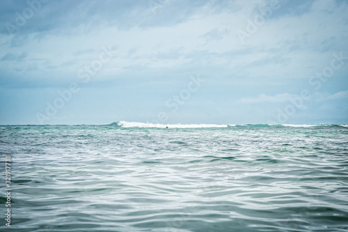 Fototapeta Naklejka Na Ścianę i Meble -  Sea wave horizon turquoise water blue dramatic overcast sky landscape surfing lifestyle