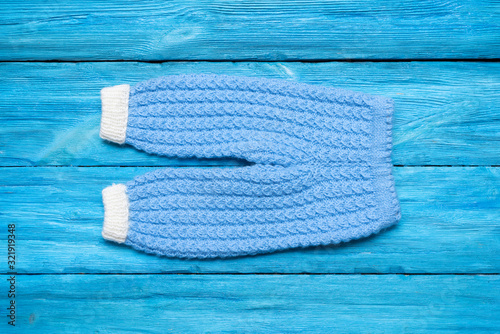 Children warm knitted clothes on blue wooden table background. photo