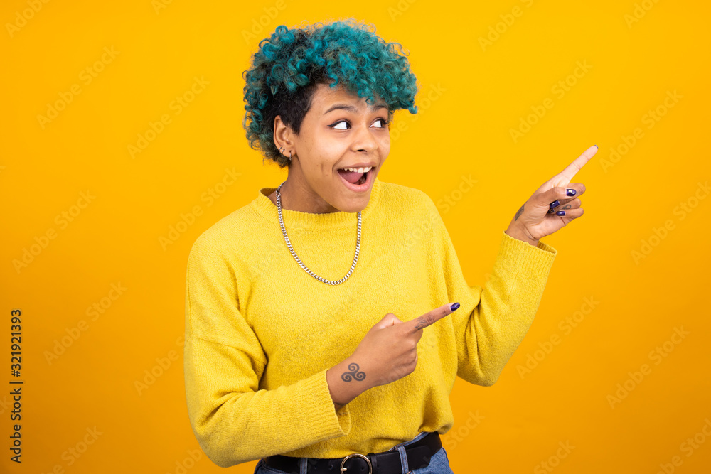 fashionable african american girl or woman with blue hair isolated on yellow background