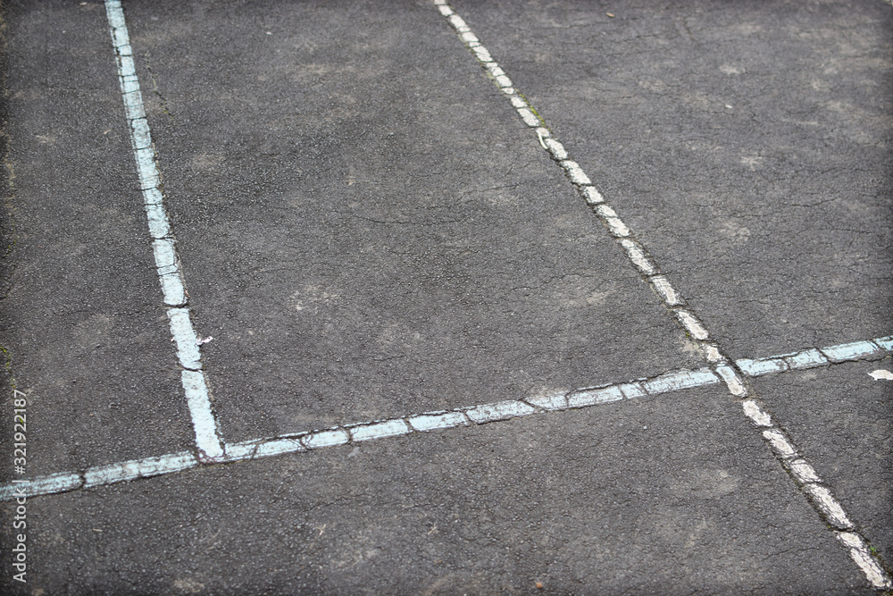 Old painted lines on a school yard ball game court surface