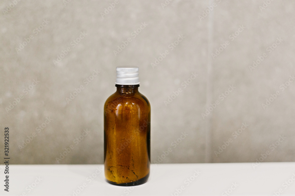 Ayurveda ubtan powder in glass bottle on white sink on background of modern grey bathroom. Natural organic essentials. Zero waste concept. Plastic free. Sustainable lifestyle Ayurveda ubtan powder in glass bottle on white sink on background of modern grey bathroom. Natural organic essentials. Zero waste concept. Plastic free. Sustainable lifestyle