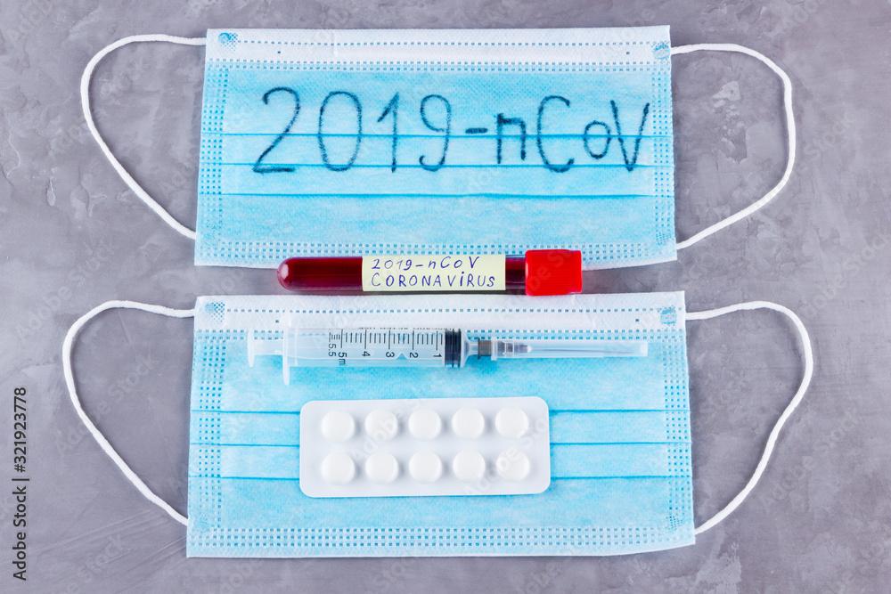 Novel coronavirus - 2019-nCoV. Test tube with blood identified by the 2019-nCoV coronavirus on gray background. Protective medical mask, thermometer and syringe Novel coronavirus - 2019-nCoV. Test tube with blood identified by the 2019-nCoV coronavirus on gray background. Protective medical mask, thermometer and syringe