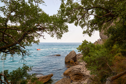 Obraz na płótnie Boat moving on the waves. View of Green Bay, coastal cliffs and a ridge of mountains on the horizon. Black Sea coast, Sudak region, Republic of Crimea w salonie