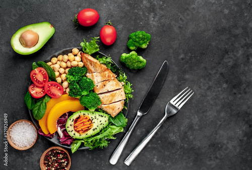 Bowl Buddha. chicken, broccoli, chickpeas, pumpkin, avocado, carrot, tomato on a stone background with copy space for your text