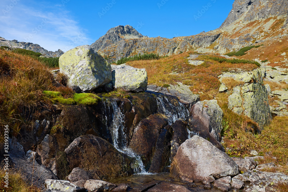 Small waterfall in autumn High Tatras mountain with stones and peaks at Skok waterfall and lake in Slovakia