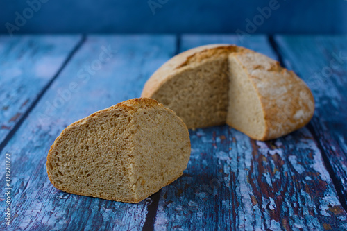 Картината върху платно A piece of tasty homemade kneaded bread in front of  the loaf, on the beautiful blue rustic background