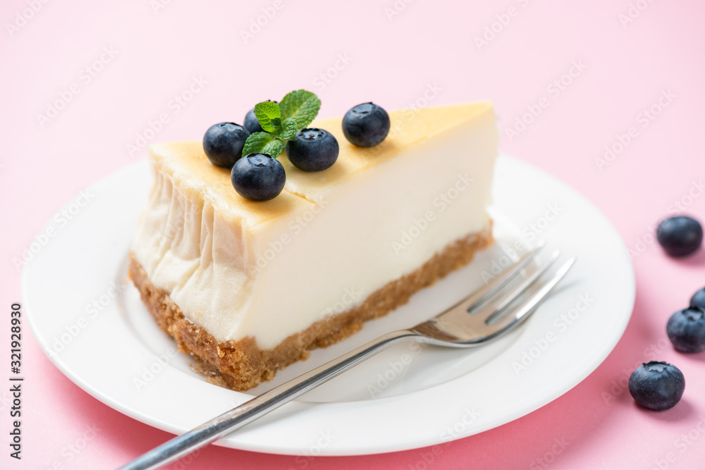 Slice of plain cheesecake with blueberries over pink background Slice of plain cheesecake with blueberries over pink background