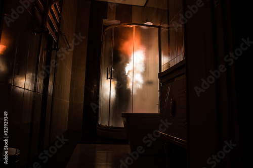 Horror silhouette of person in window. Scary halloween concept Blurred silhouette of witch in bathroom. Decorated with fireworks