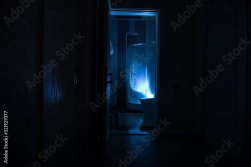 Horror silhouette of person in window. Scary halloween concept Blurred silhouette of witch in bathroom. Decorated with fireworks