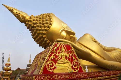 Head of Reclining Gold Covered Buddha Statue or The Great Stupa, a sacred Buddhist Monument in Pha That Luang, Vientiane, Laos capital
