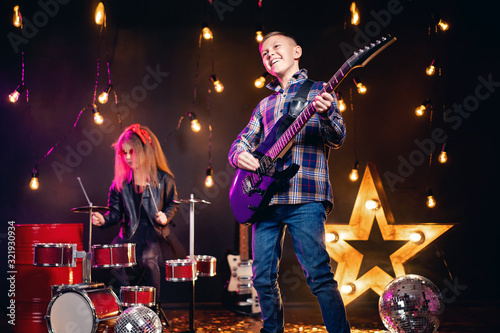 Fotografie Kids pretending to be in a rock band and play and sing at studio or stage