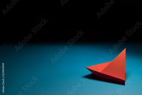 Red paper sailing ship on blue background