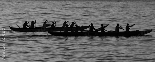 Outrigger canoe crews at sunrise at Waikiki in monochrome as silhouettes