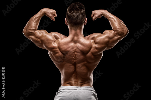 Muscular man showing back muscles rear view, isolated on black background. Strong male naked torso photo