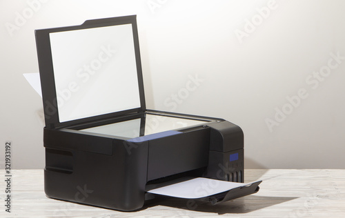 Black copier on white wooden table, closeup.