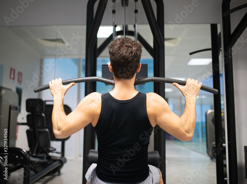 Man using a lat machine in a gym to train his shoulders and back