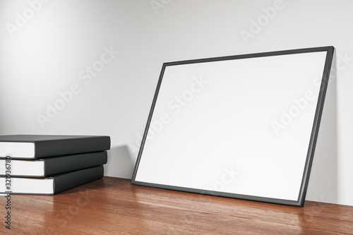 Blank poster and books standing on wooden floor