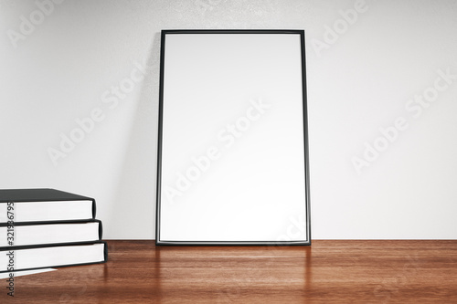 Empty poster and books standing on wooden floor
