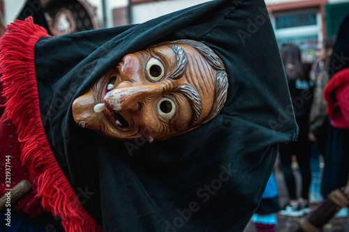 Troepfle Hexen aus Bad Rippoldsau - Hübsche Hexe mit schwarzer Kopfhaube und rot, blauem Gewand schaut frech mit geneigtem Kopf in die Kamera. Bei Fastnachtumzug in Staufen Süd Deutschland. photo