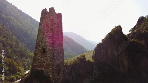 Aeriel video from drone Caucasian battle tower at sunset on a background of mountains around greens 4k photo