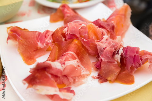 prosciutto with melon on a white plate