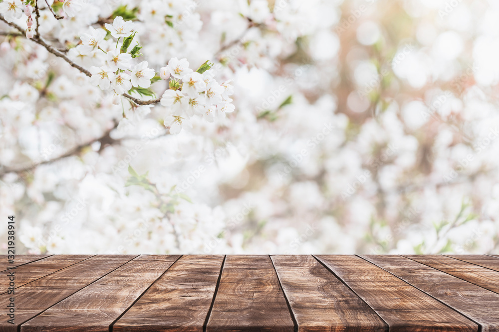 Plakat Pusty drewniany blat i niewyraźne drzewo kwiat sakury w tle ogrodu z filtrem vintage - może służyć do wyświetlania lub montażu produktów.