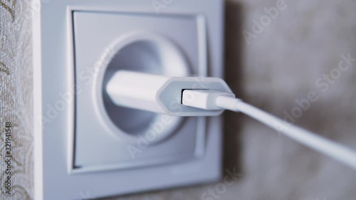 Man hand plug in charger adapter into wall socket close up
