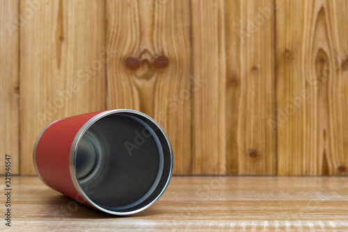 Red colour stainless steel tumbler or cold and hot storage cup on wood.