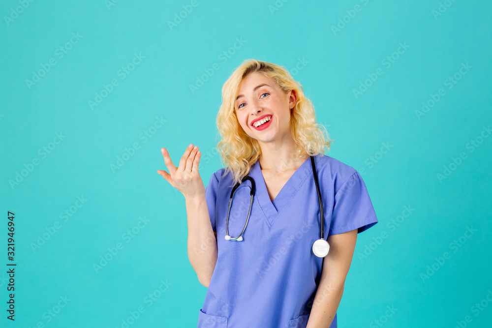 Close up studio portrait of a smiling young female doctor or nurse wearing blue scrubs and stethoscope, pointing up Close up studio portrait of a smiling young female doctor or nurse wearing blue scrubs and stethoscope, pointing up